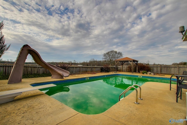 view of swimming pool with a gazebo, a water slide, and a diving board