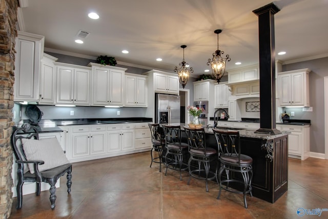 kitchen with a breakfast bar, stainless steel fridge with ice dispenser, hanging light fixtures, an island with sink, and white cabinets