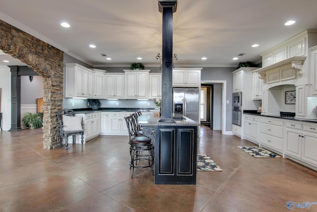 kitchen with crown molding, appliances with stainless steel finishes, a kitchen breakfast bar, white cabinets, and a kitchen island