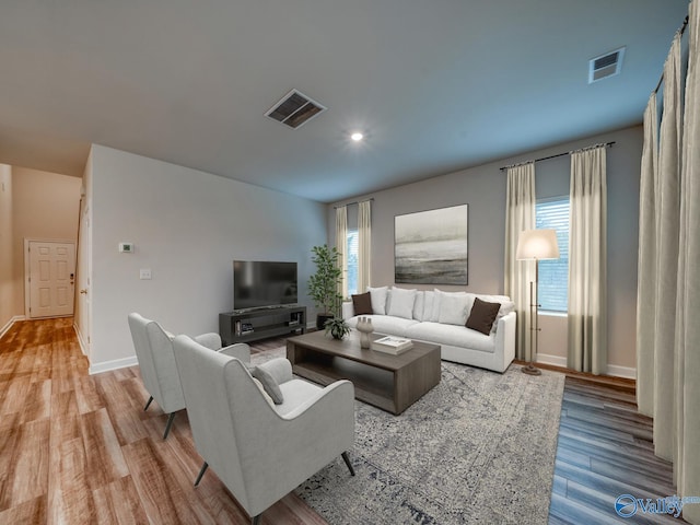 living room with light wood-style flooring, visible vents, baseboards, and recessed lighting