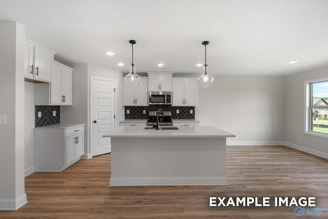 kitchen featuring light countertops, tasteful backsplash, appliances with stainless steel finishes, and a sink