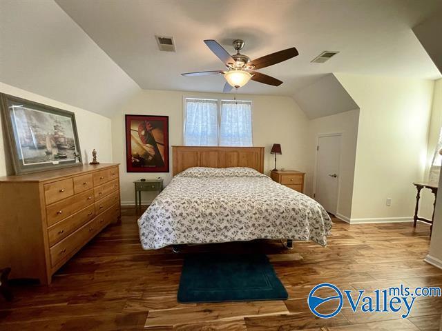 bedroom with wood finished floors, baseboards, and visible vents