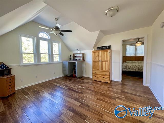 additional living space featuring wood finished floors, baseboards, a ceiling fan, and vaulted ceiling