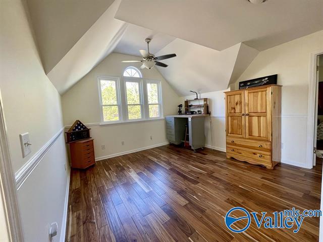 additional living space featuring dark wood-style flooring, baseboards, a ceiling fan, and lofted ceiling