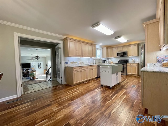 kitchen featuring visible vents, a ceiling fan, crown molding, stainless steel appliances, and dark wood-type flooring