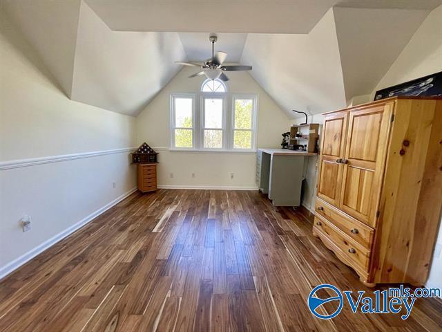 additional living space featuring baseboards, dark wood-type flooring, vaulted ceiling, and a ceiling fan