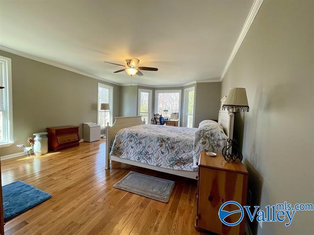 bedroom with crown molding, wood finished floors, baseboards, and a ceiling fan