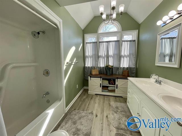 full bath featuring vaulted ceiling,  shower combination, wood finished floors, a sink, and double vanity