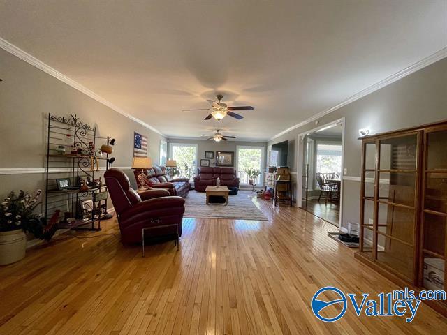 living room with wood-type flooring, a ceiling fan, and crown molding