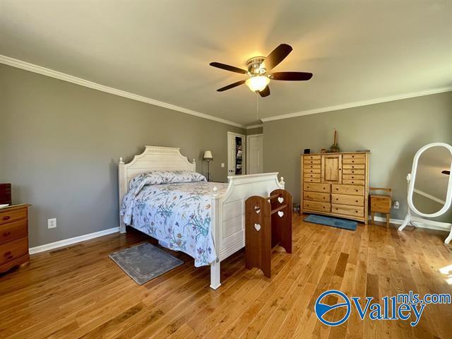 bedroom with crown molding, baseboards, ceiling fan, and wood finished floors
