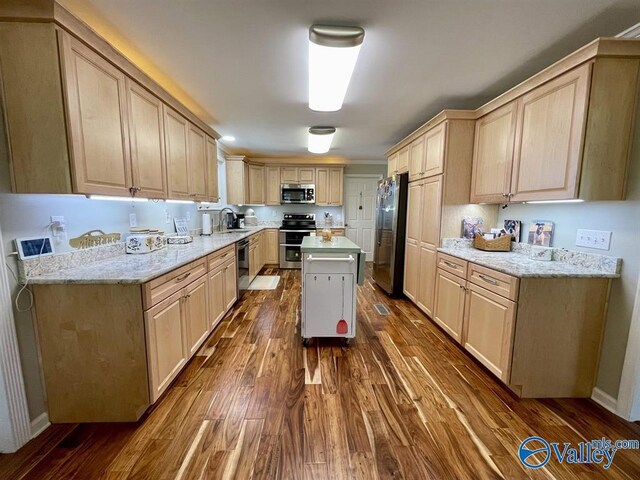 kitchen with stainless steel appliances, dark wood-style flooring, a sink, and light brown cabinetry