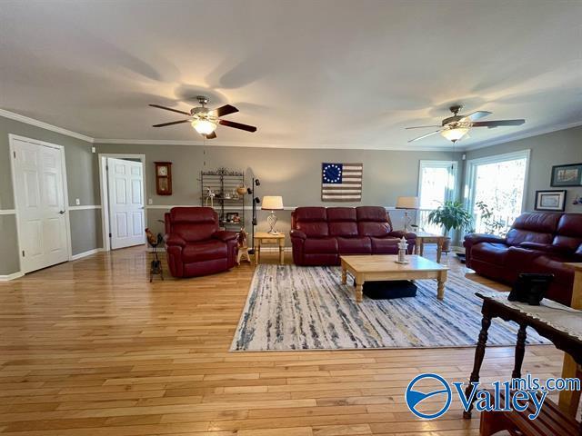 living area with ornamental molding, a ceiling fan, and wood finished floors