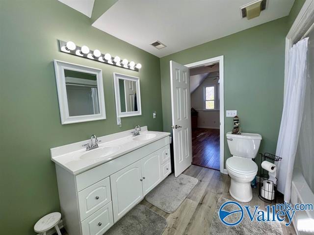 full bathroom featuring a sink, visible vents, double vanity, and wood finished floors
