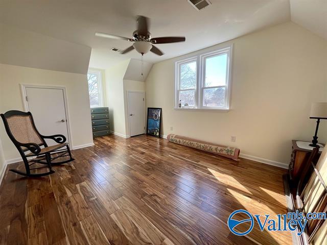 additional living space with dark wood-style floors, a healthy amount of sunlight, a ceiling fan, and vaulted ceiling