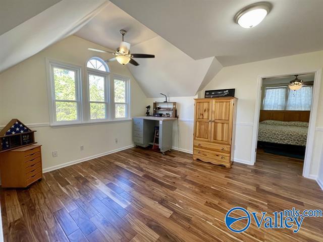 additional living space featuring wood finished floors, baseboards, a ceiling fan, and vaulted ceiling