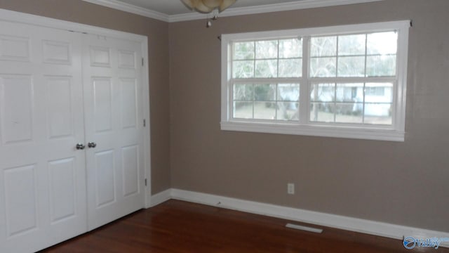 unfurnished bedroom with multiple windows, a closet, and dark wood-type flooring