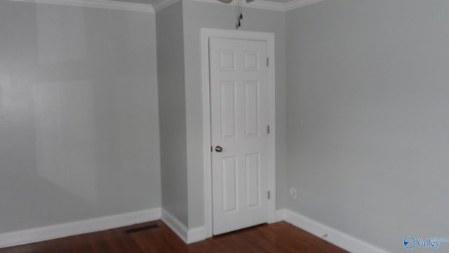 spare room featuring dark wood-type flooring and ornamental molding