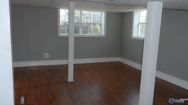 basement with a paneled ceiling and dark hardwood / wood-style floors