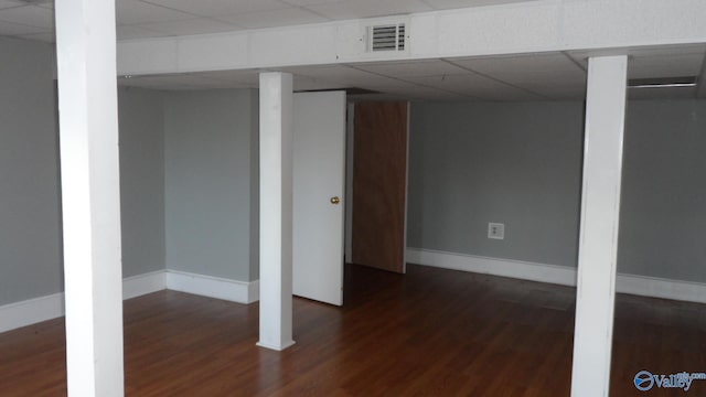 basement featuring a drop ceiling and dark wood-type flooring