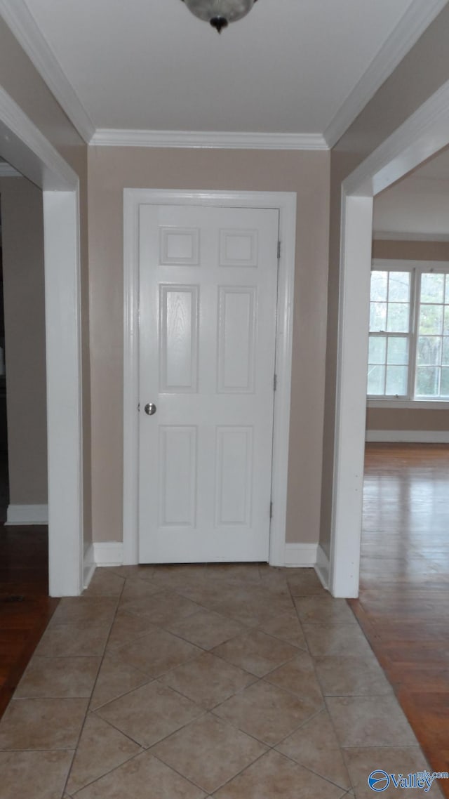 foyer with light tile patterned floors and crown molding