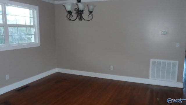 unfurnished dining area with dark wood-type flooring, crown molding, and a notable chandelier