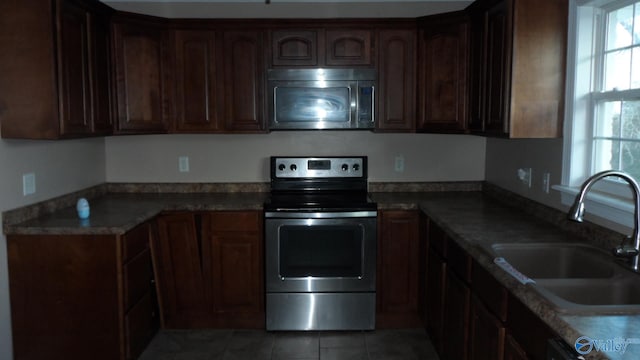 kitchen featuring sink, dark tile patterned flooring, stainless steel electric range, and stone countertops