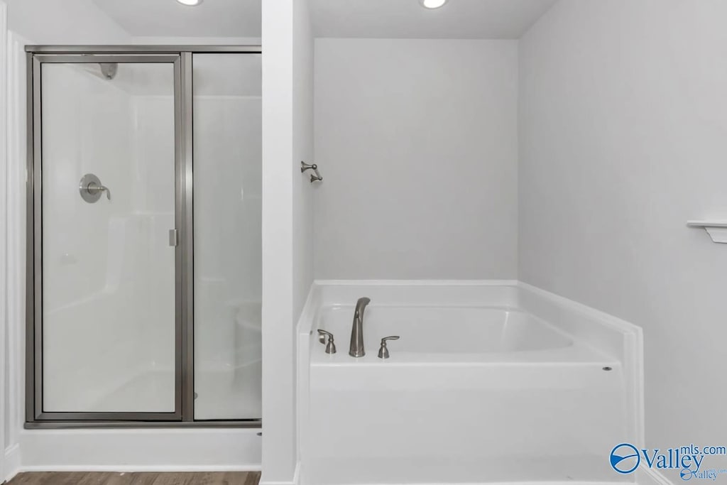 bathroom featuring wood-type flooring and plus walk in shower