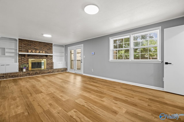 10012 Allison Dr, Huntsville, AL 35803 - unfurnished living room with built in shelves, light wood-type flooring, baseboards, a brick fireplace, and ornamental molding