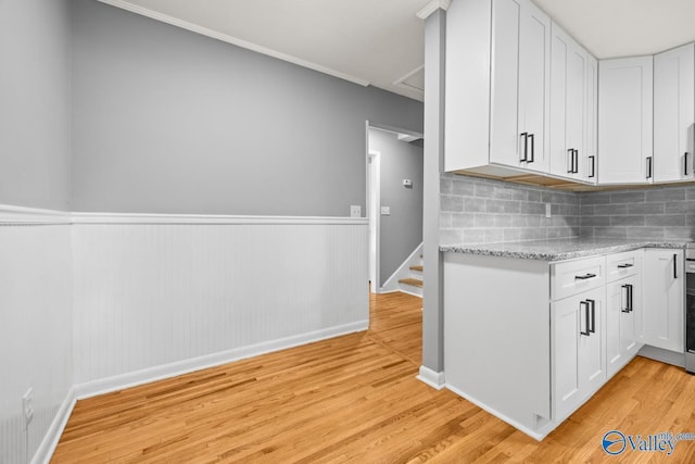 10012 Allison Dr, Huntsville, AL 35803 - kitchen featuring light wood-style flooring, baseboards, white cabinetry, a wainscoted wall, and crown molding