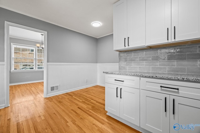 10012 Allison Dr, Huntsville, AL 35803 - kitchen with crown molding, light wood-type flooring, backsplash, light stone counters, and white cabinets