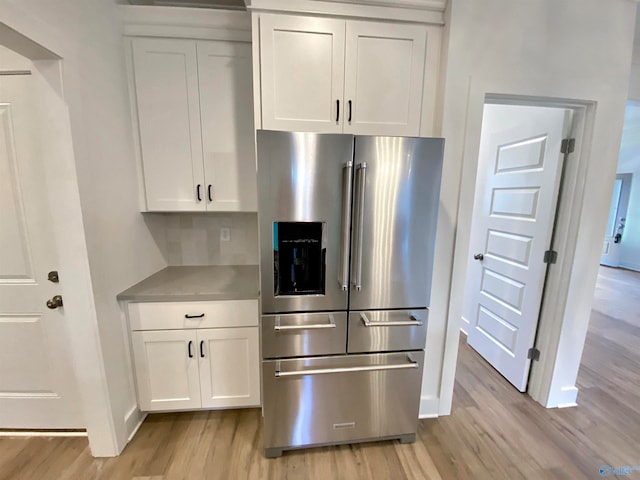 kitchen with white cabinets, backsplash, light hardwood / wood-style flooring, and stainless steel refrigerator with ice dispenser