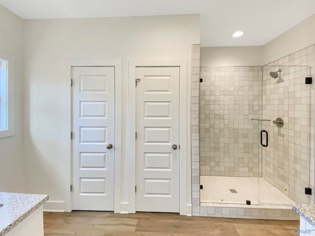 bathroom with a shower with door, vanity, and wood-type flooring