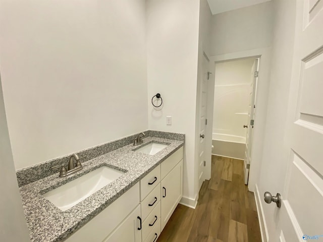 bathroom with dual vanity, shower / washtub combination, and hardwood / wood-style flooring