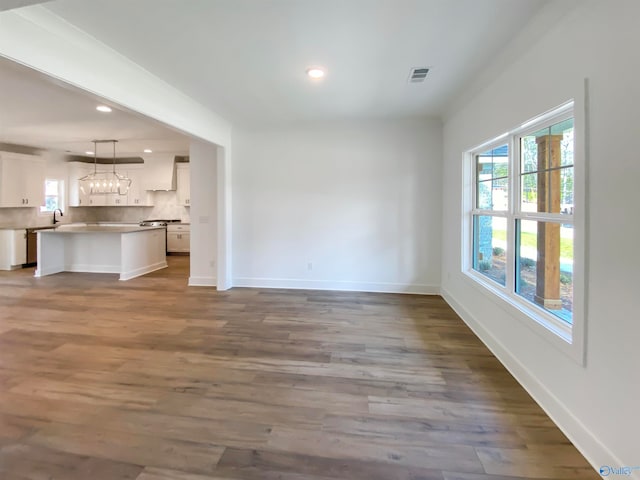 unfurnished living room featuring plenty of natural light, sink, and hardwood / wood-style flooring