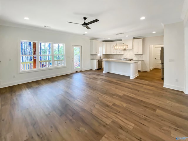 unfurnished living room with ceiling fan, sink, dark hardwood / wood-style flooring, and crown molding