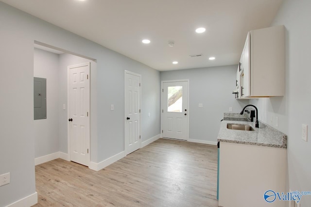 3913 Pine Ave SW, Huntsville, AL 35805 - kitchen with light wood-style floors, baseboards, electric panel, light stone counters, and a sink