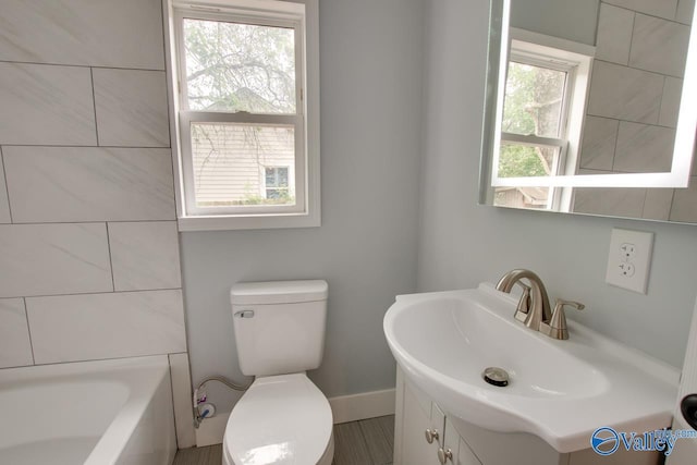 3913 Pine Ave SW, Huntsville, AL 35805 - full bathroom featuring a tub, vanity, baseboards, and toilet