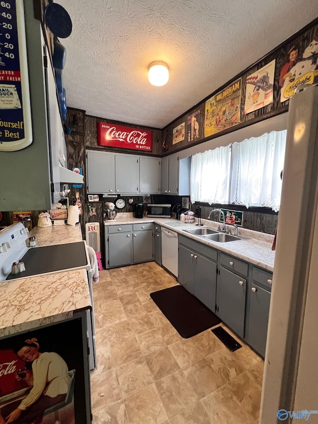 kitchen featuring gray cabinets, dishwasher, sink, and a textured ceiling