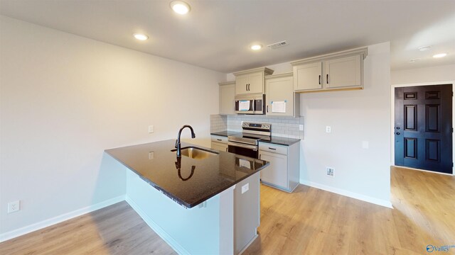 kitchen featuring decorative backsplash, sink, kitchen peninsula, light hardwood / wood-style flooring, and appliances with stainless steel finishes