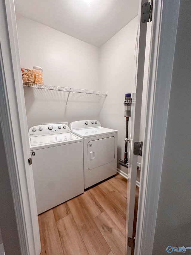 clothes washing area with washer and clothes dryer and light hardwood / wood-style floors