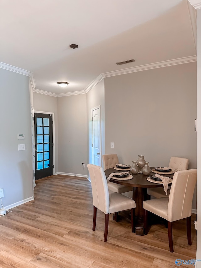 dining area featuring crown molding and light hardwood / wood-style flooring