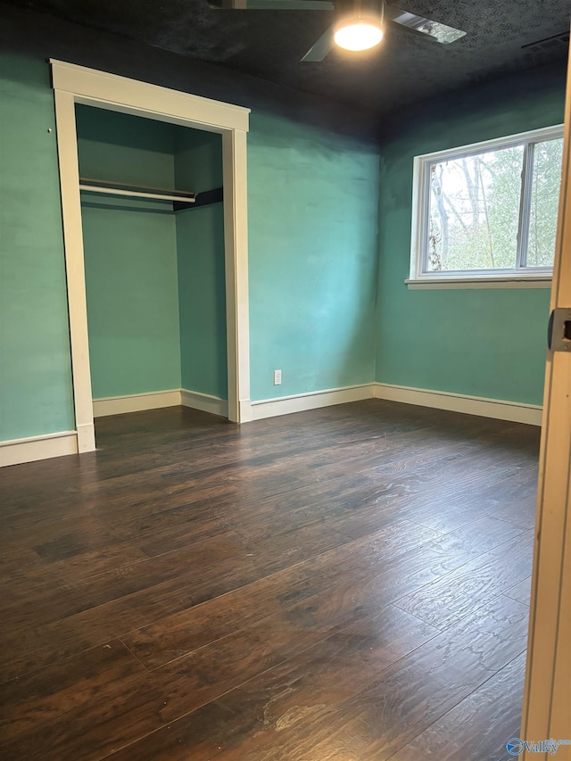 unfurnished bedroom with dark hardwood / wood-style flooring, a closet, and ceiling fan