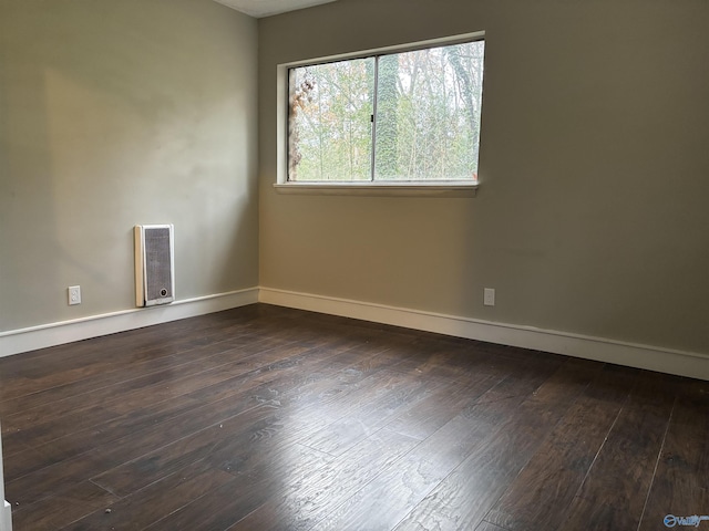 empty room with heating unit and dark hardwood / wood-style floors