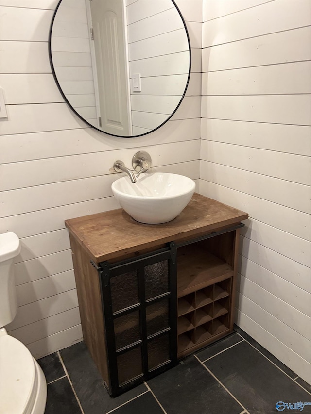 bathroom featuring wood walls, tile patterned flooring, vanity, and toilet