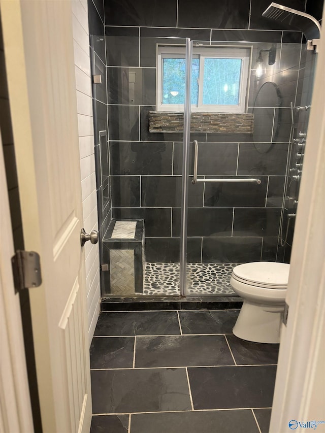 bathroom featuring tile patterned flooring, toilet, and a shower with shower door