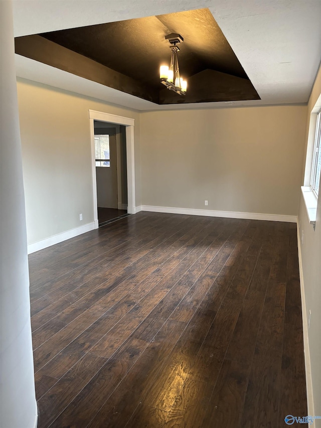 unfurnished room with a raised ceiling and dark wood-type flooring