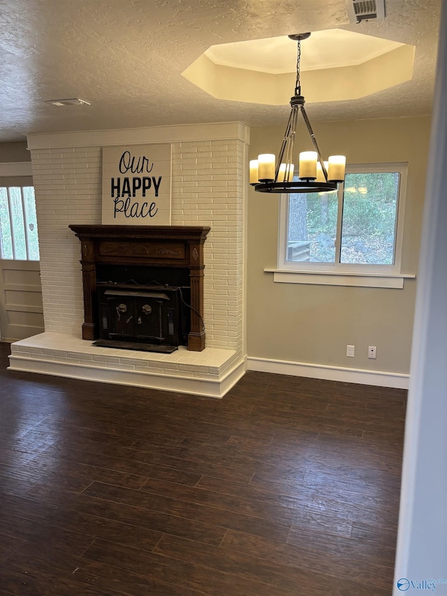 unfurnished living room featuring a notable chandelier, dark wood-type flooring, a wealth of natural light, and a tray ceiling