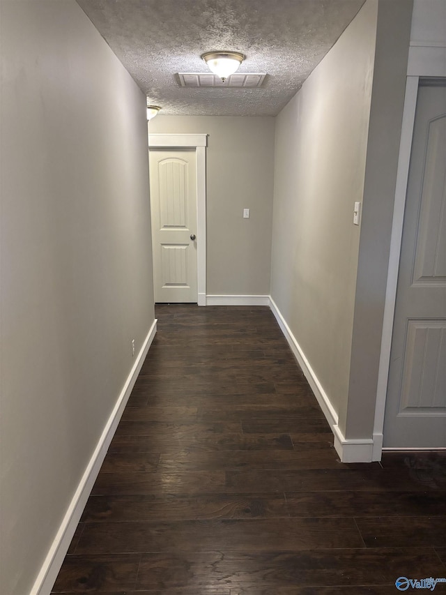 corridor featuring a textured ceiling and dark hardwood / wood-style floors