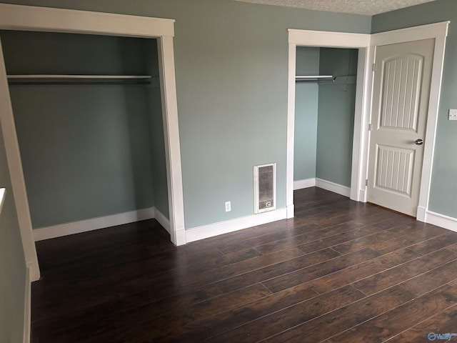 unfurnished bedroom with a textured ceiling and dark wood-type flooring