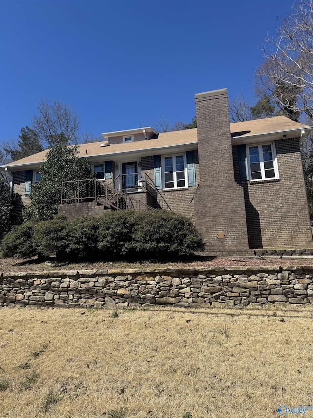 back of house featuring brick siding and a chimney